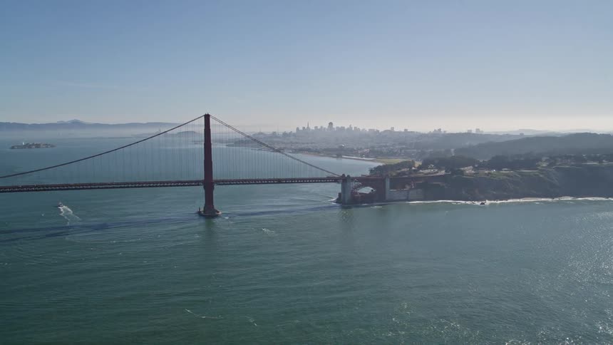 Aerial panorama of a long bridge over the sea connecting cities and a metropolis on the horizon