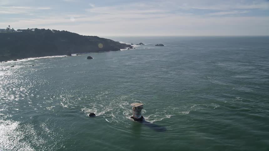 Waves crash against the shore of the island
