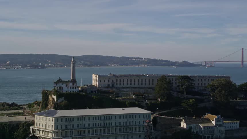 An aerial view of an island complex with a large city and the golden gate bridge behind it
