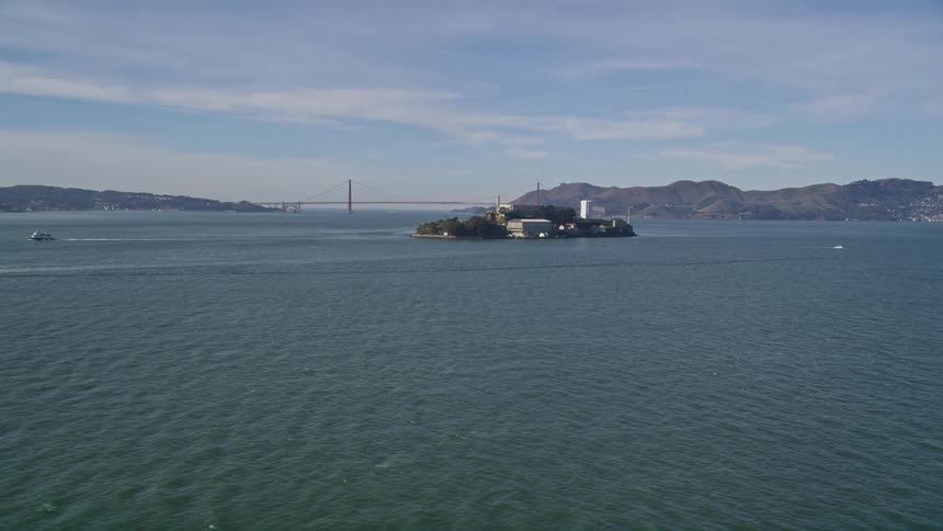 Boats move away from an island prison near a city and bridge