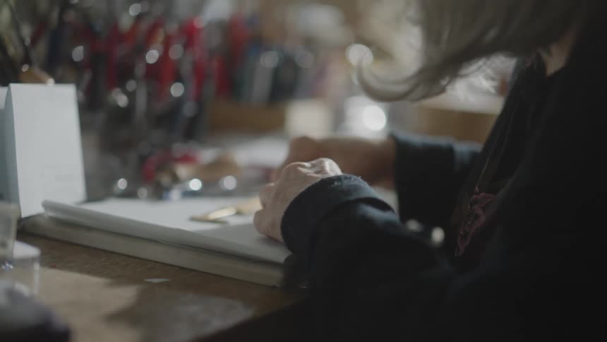 Elderly woman wearing magnifying glasses crafting on a workbench