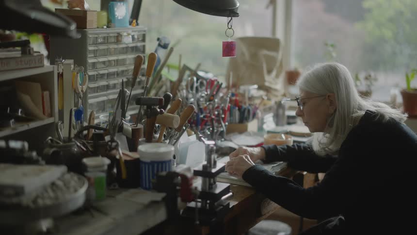 Lady sitting at a table with equipment and concentrating on an abstract object that moves her with her hands