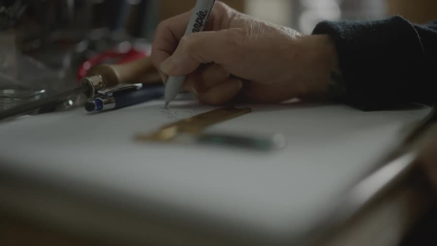 A person is drawing on a paper with a pen
