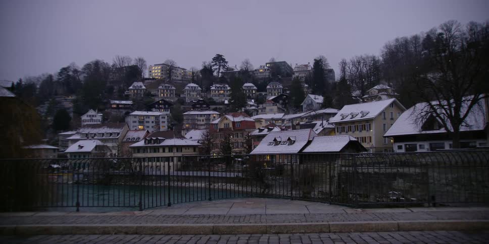 View of Bern, Switzerland neighborhood across the Aare River at dusk in winter.