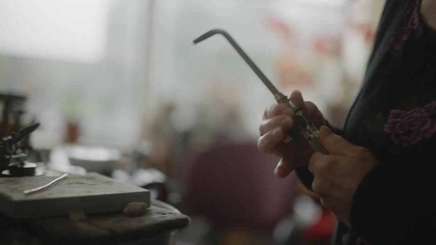 A womans hands adjusting a blowtorch