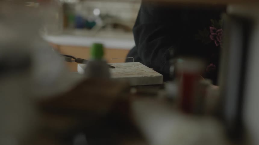 An elderly woman paints in a kitchen