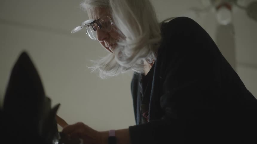 Lady hammering an abstract object indoors