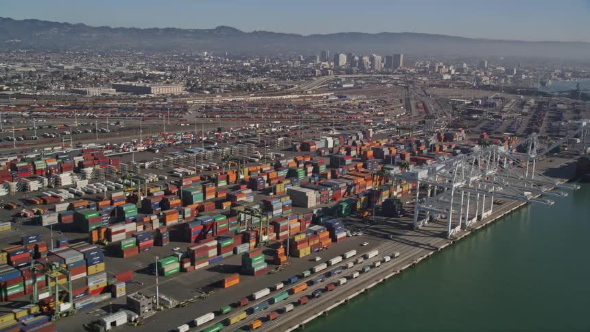 An aerial view of a busy riverside shipping port with a big city behind it