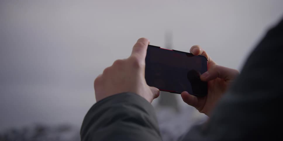 A person holding a smart phone filming the Bern, Switzerland city skyline on a cloudy winters day