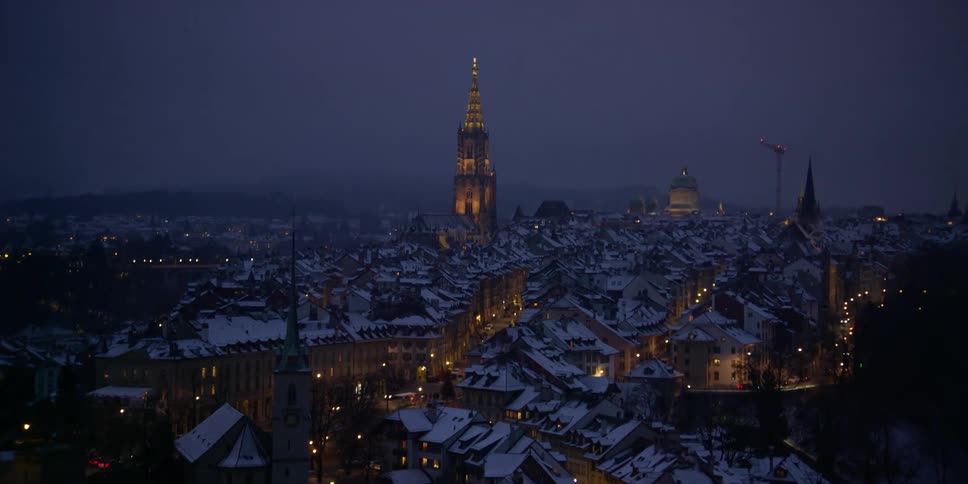 The city of Bern in Switzerland at night blanketed in snow with church spires dotting the landscape