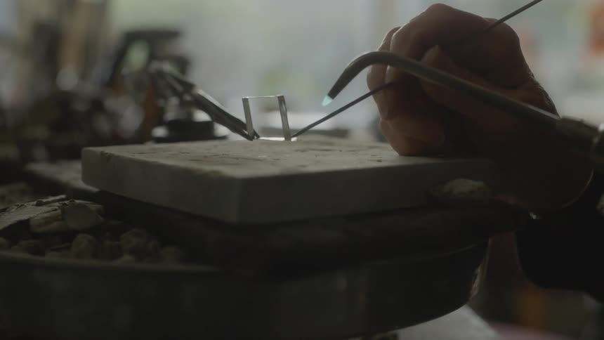 A person soldering a piece of metal over a slab in the workshop