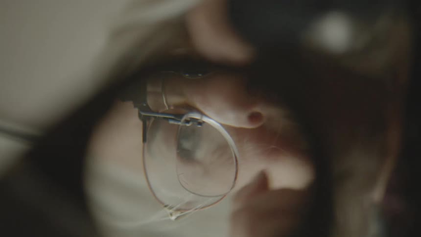 Point of view of a magnifying glass with a lady looking concentrated with prescription glasses