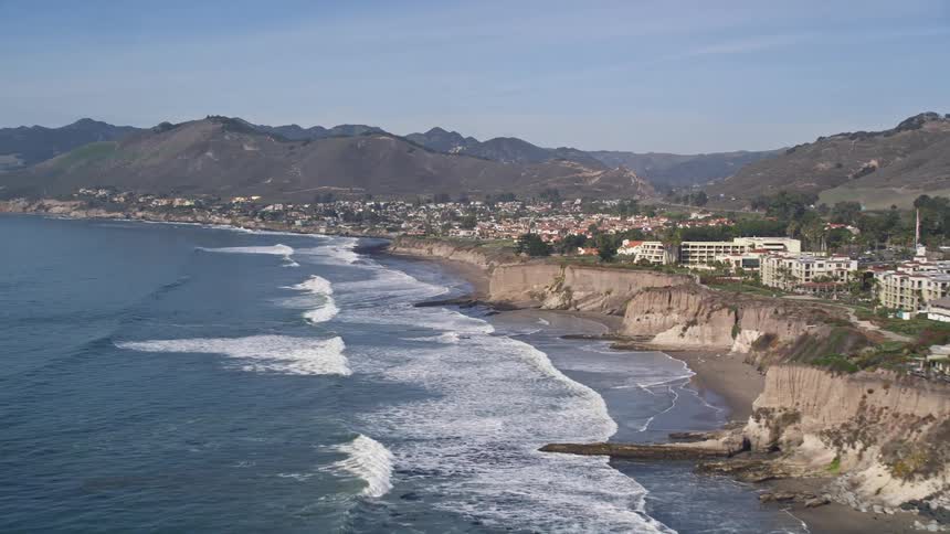 Waves crash ashore near a coastal town