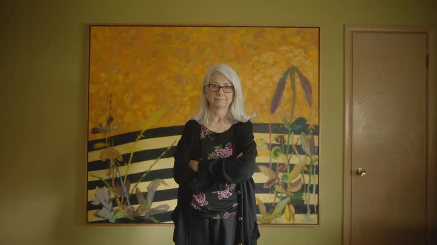 A portrait of an artist standing in front of her art