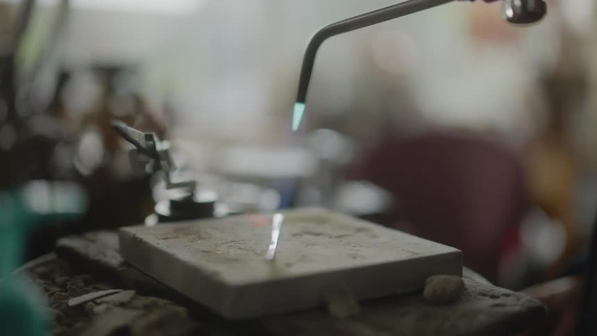 Closeup of a blowtorch being passed over a small metal rod