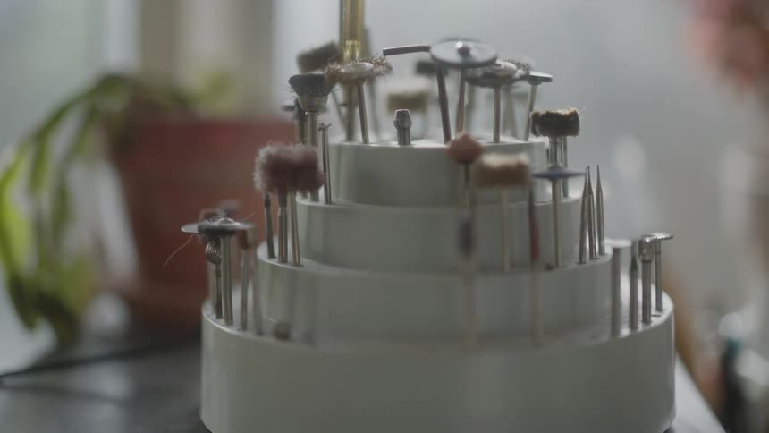 Closeup of a white pot with tools of different sizes on a workbench