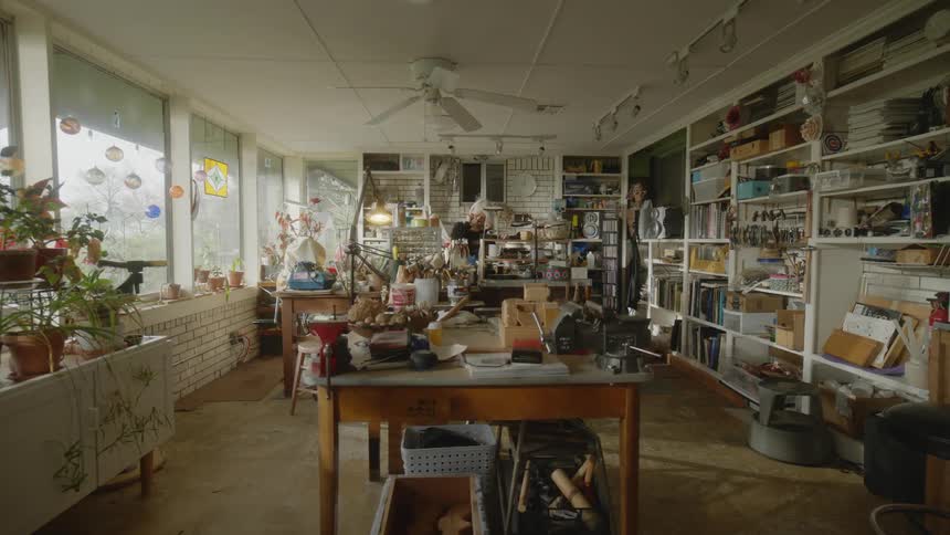 An artist working in a cluttered but spacious studio