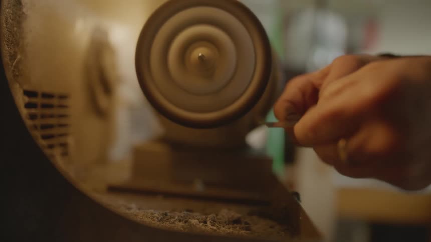 Woman hands shaping a small silver rod in a machine