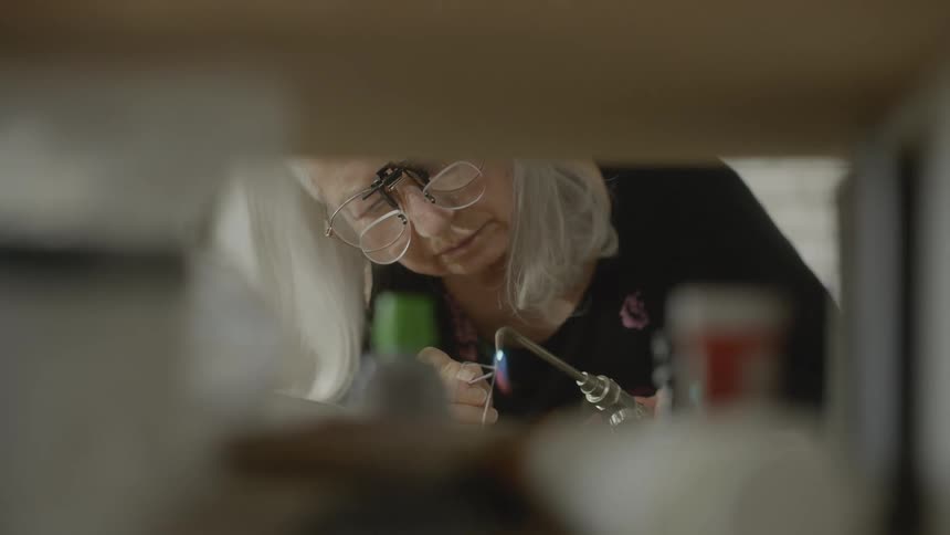 Old lady heating a steel needle with a blowtorch