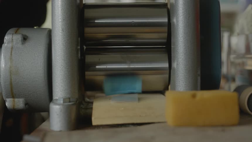 An artist rolls an object through a machine