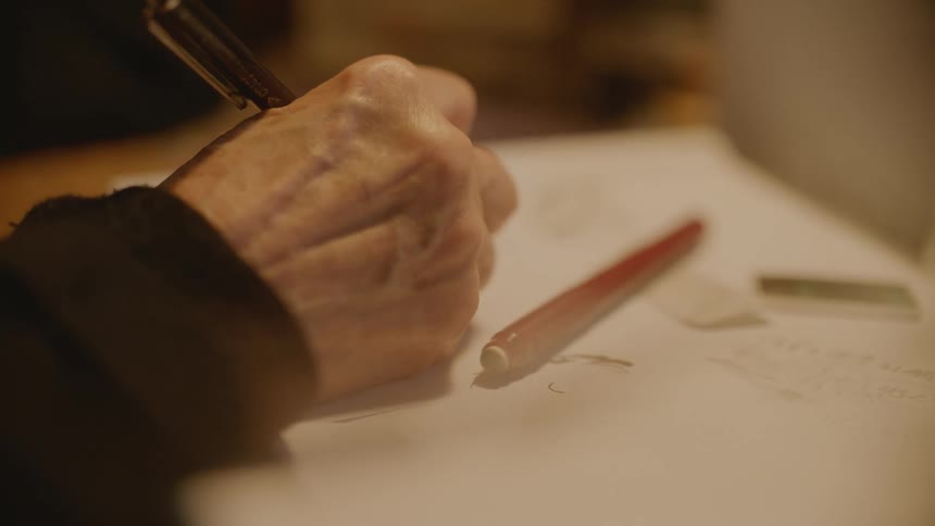 A person is writing on a paper with a pen