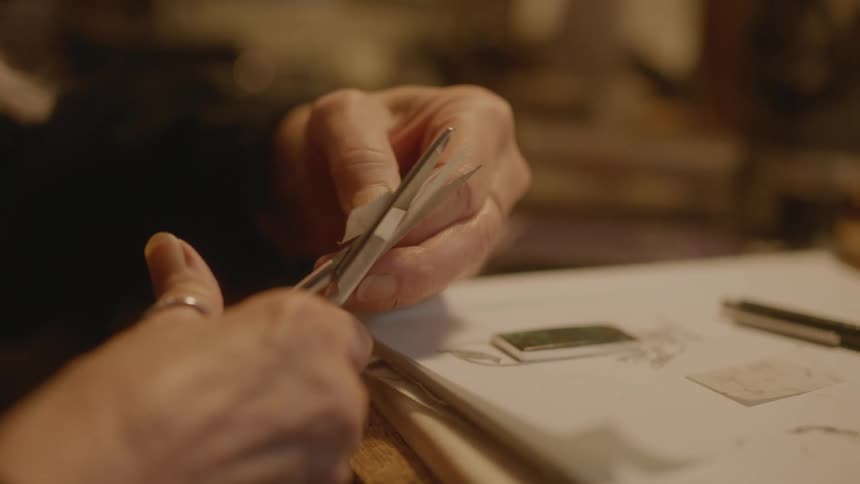 Closeup of a womans hands cutting with scissors on paper