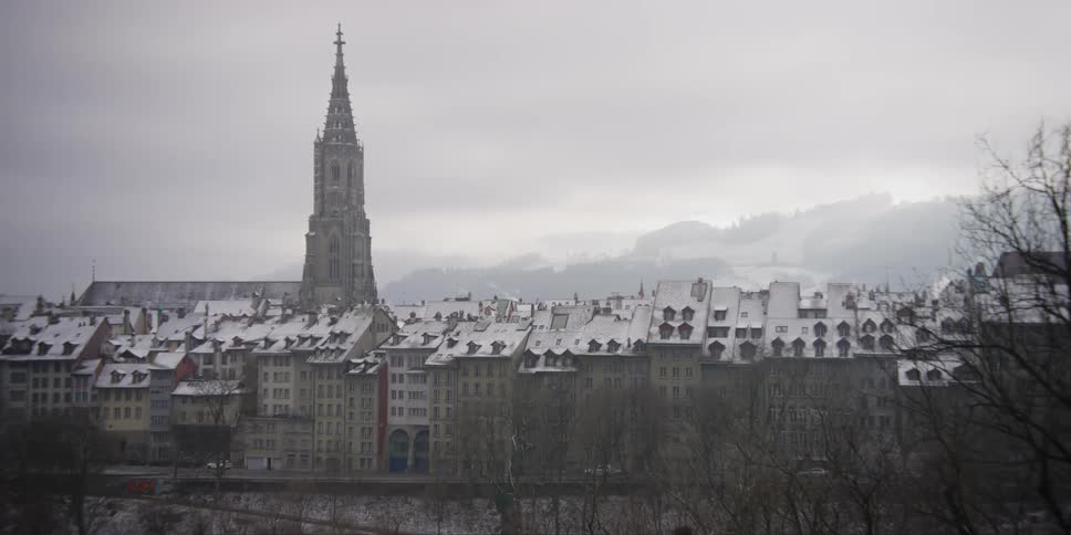 Distant view of the bell tower of the Bern Minster towering over nearby homes in Bern, Switzerland