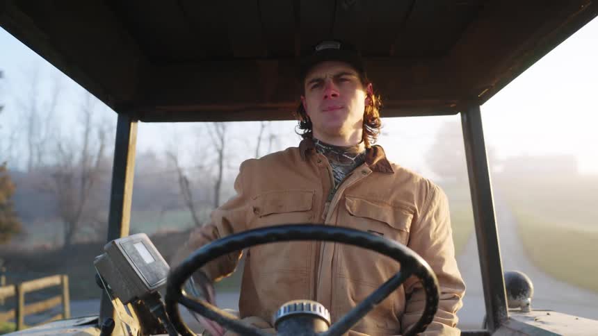 Man sitting inside a tractor on a farm at morning