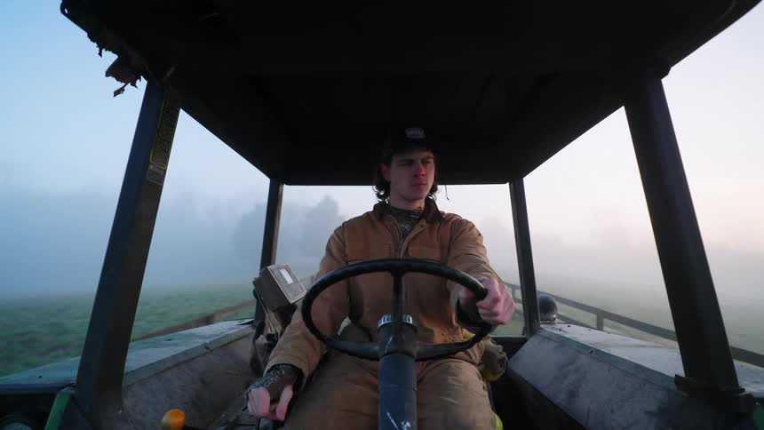 A farmer drives a tractor down a lane