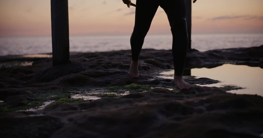 A man is carrying his surfboard on the beach