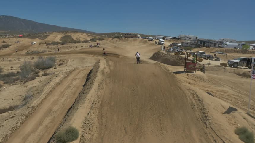 Aerial view of motocross riders race and jumps around a dirt track