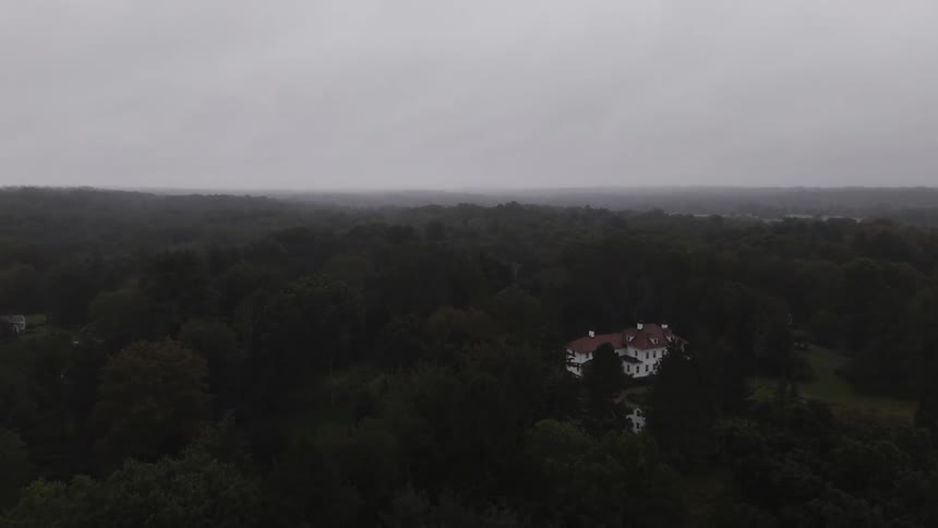 Aerial panorama of a house in a forest on a cloudy day