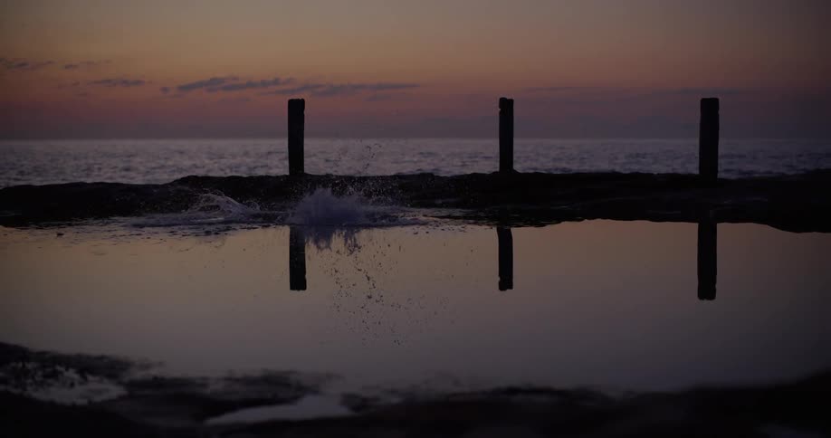 Silhouette of a person diving on a tidal pool at sunset