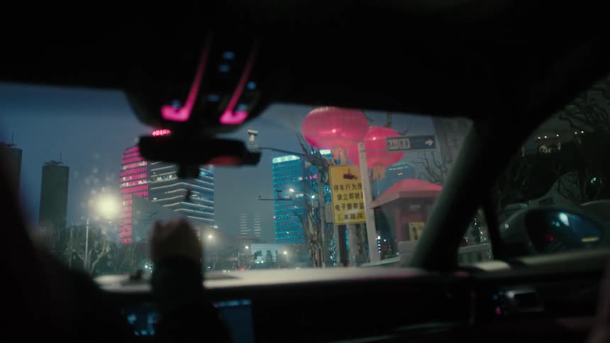 Interior of the windshield of a vehicle moving through a metropolitan city with skyscrapers at night