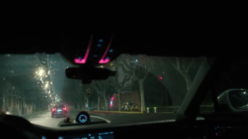 Interior of a vehicle by a city street on a rainy day at night