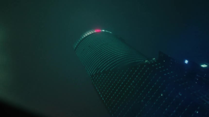 Skyscrapers on a foggy night seen from a moving vehicle