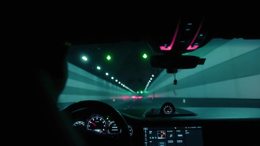 Cars drive through tunnel lit by overhead lights