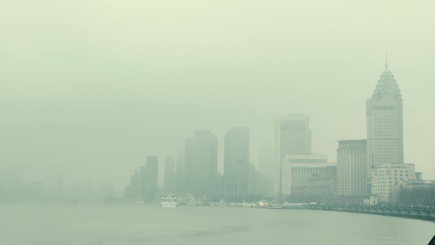 Large boat floats in water near fog shrouded downtown skyscrapers