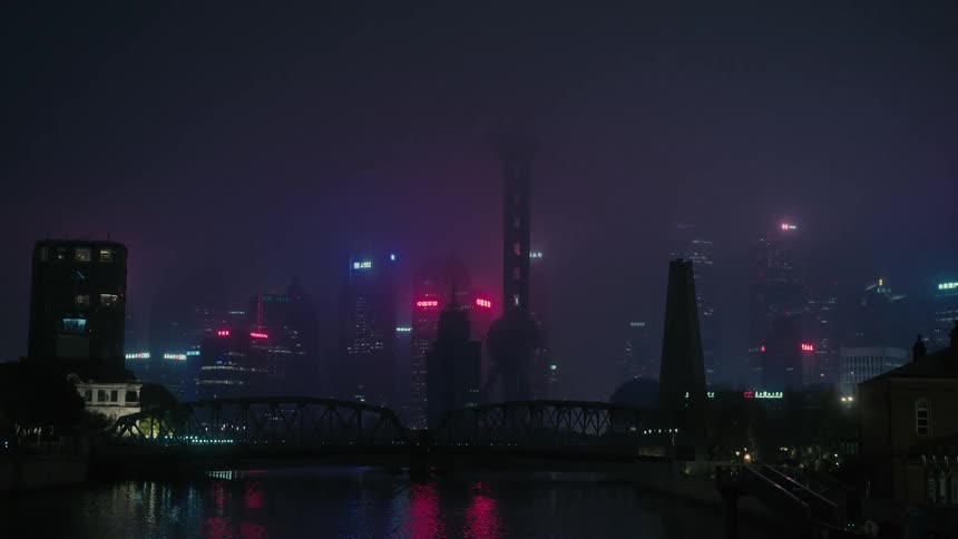 Panorama of a city with modern buildings and skyscrapers by the sea on a foggy night