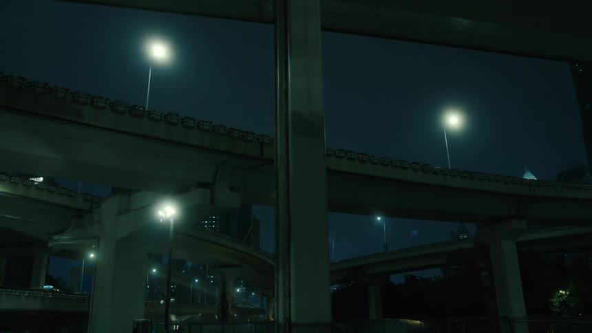 Vehicles drive along network of freeways near city buildings at night