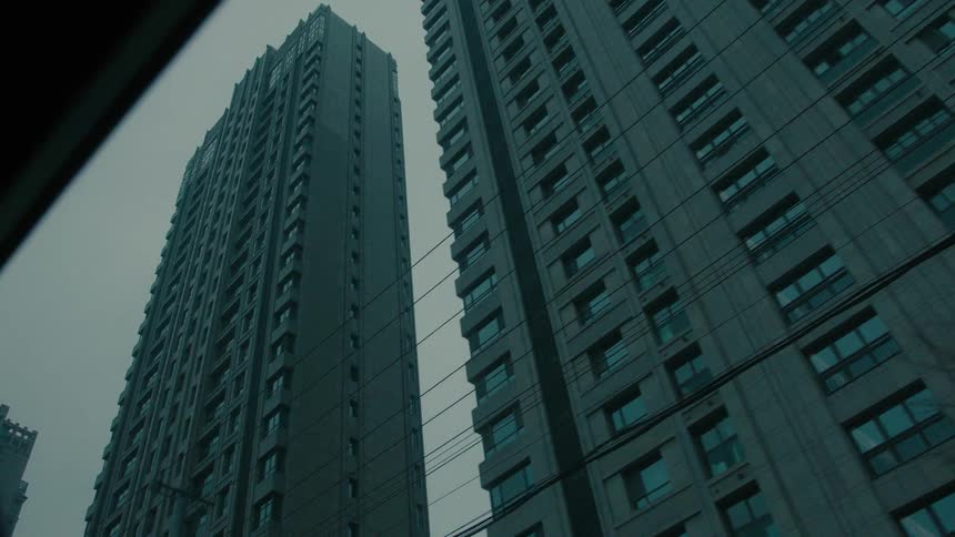 View from inside a vehicle in a city with large urban and commercial buildings on a cloudy day