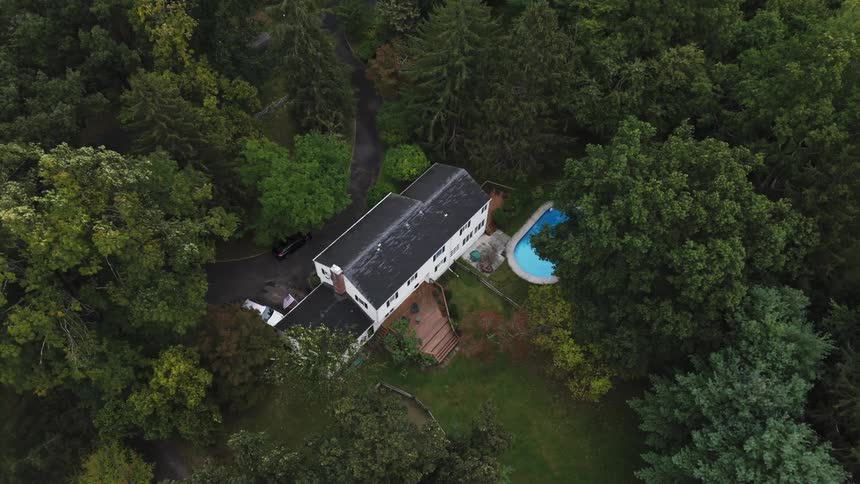 Aerial view of a house surrounded by trees during the day