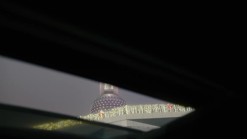 View from the sunroof of a car at the pearl of the orient tower illuminated at night