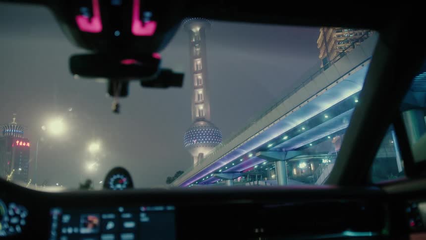Windshield inside a car moving through a metropolis with modern skyscrapers at night