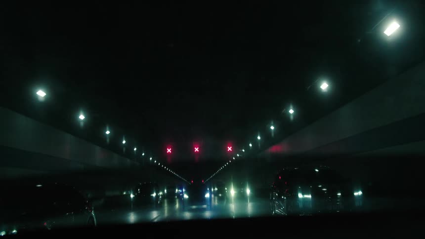 Various cars drive through a dark tunnel