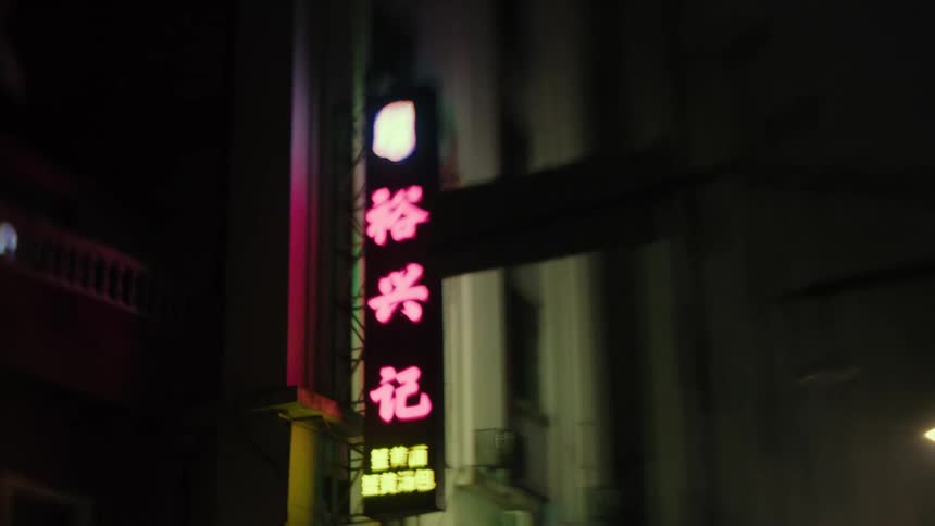 A sign with asian text with some lights in a wall at night