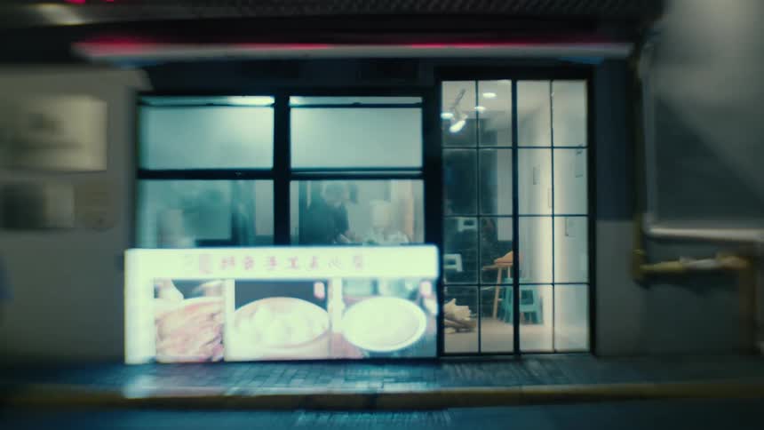Pedestrians walk past a restaurant in the city streets at night