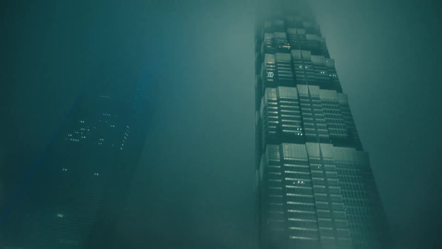 Skyscrapers lit at night surrounded by fog