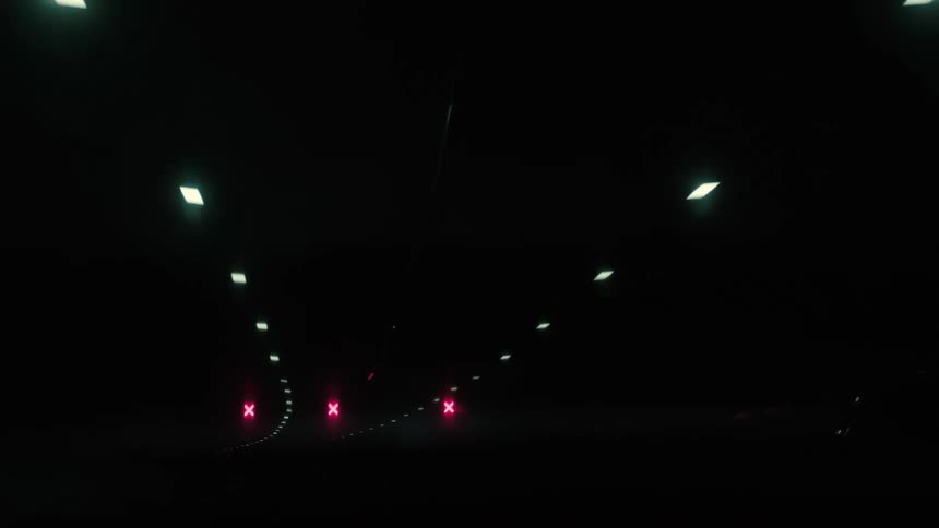Point of view from the window of a moving car passing through a tunnel through the city at night