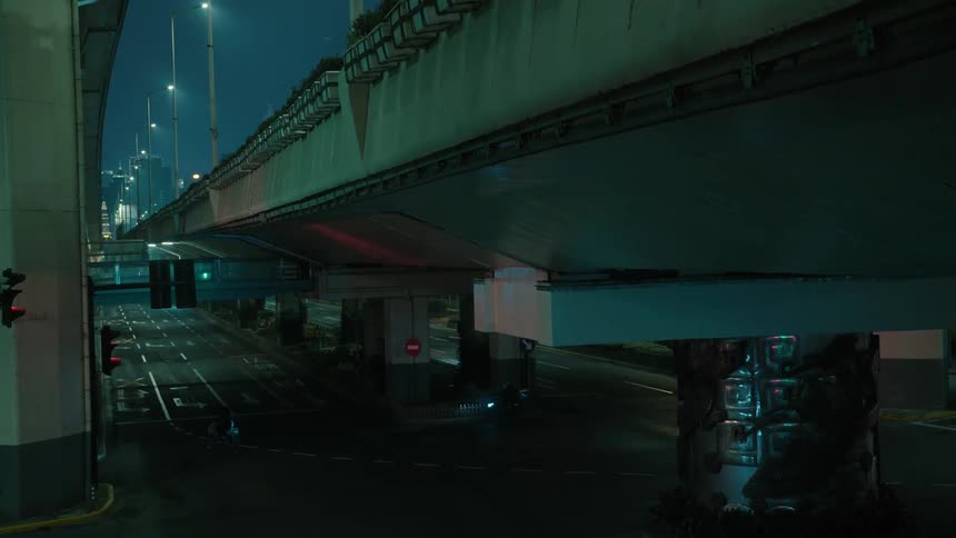A person is walking under the dark overpass